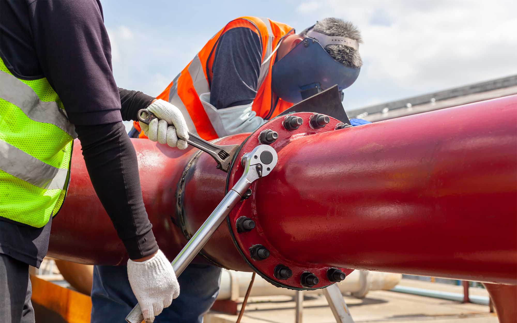 Union pipefitters work on a pipe on a construction site