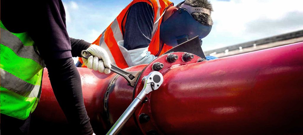 Union pipefitters work on a pipe on a construction site